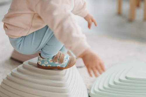 Dziecko w ruchu w trampkach Blue Daisy, widoczna przyczepność podeszwy na podwyższeniu.