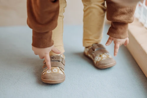 Dziecko wskazuje paluszkiem na wzór stokrotki na nosku trampka Titot.