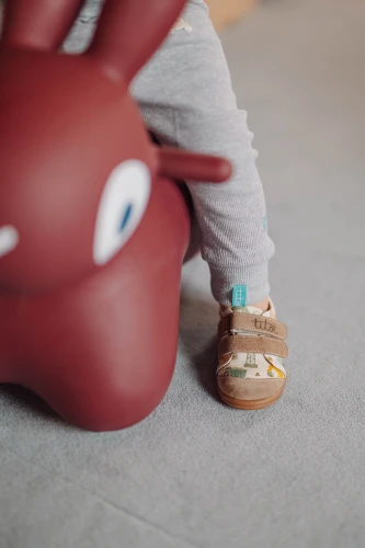 Noga dziecka w trampku City Builders obok czerwonego gumowego skoczka.