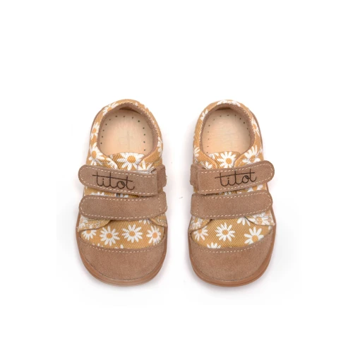 Widok z góry na parę tenisówek w stokrotki, prezentujący wnętrze i skórzane wkładki.