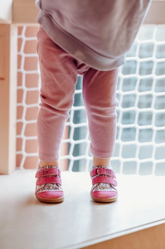 Dziecko w fioletowych kapciach w jednorożce Rainbow Unicorn i różowych legginsach.