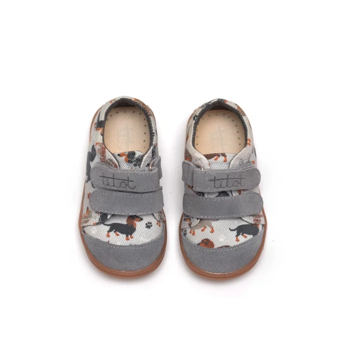 Dziecięce tenisówki Furry Doggy w jamniki, widok z przodu na szare noski i zapięcia.